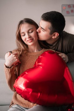 Evde ellerinde kalp şeklinde bir balon tutan aşık bir erkek ve kadının portresi. Romantik anlar. Sevgililer Günün Kutlu Olsun.