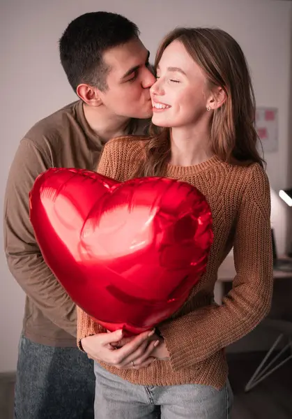 Sevgililer günün kutlu olsun. Genç bir çift ellerinde kalp şeklinde bir balon tutarak evdeki oturma odasında birbirlerine sevgiyle bakıyorlar. Evde tarih