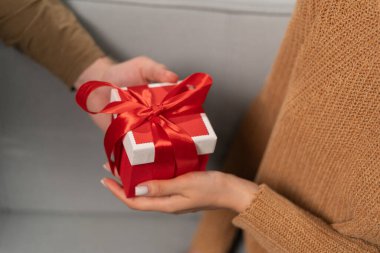 Sevgililer Günü kutlaması konsepti. Birlikte romantik bir akşam. Erkek, oturma odasındaki kanepede otururken sevgilisine bir hediye kutusu verir. Boşluğu kopyala