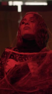 Attractive witch lady with make-up in a black lace dress in an old abandoned castle in red lighting. witch woman. Halloween. Vertical video. Vertical video