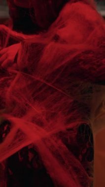 Terk edilmiş bir binada kırmızı ışığı olan bir cadı ağa takıldı. Cadılar Bayramı ve fantezi. Dikey video