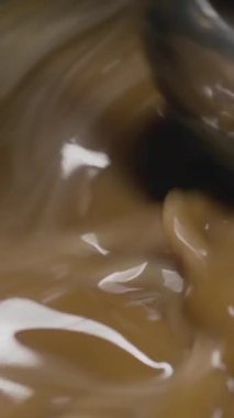 Bir tencerede karamel pişirme işlemine yakın çekim, bir şekerleme ortamında süt karamel hazırlamaya odaklanma. Dikey video