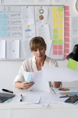 Yoğun işte evrak aramak, küçük ofisinde çalışmak için yığınla kağıt dosyayla çalışan yaşlı iş kadını. Boşluğu kopyala