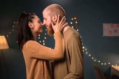 Akşam karanlık odada öpüşen genç bir çift, duvarlarında ışıklarla. Boşluğu kopyala