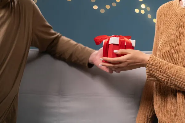 stock image Close-up shot of two hands exchanging beautifully wrapped gift box with red ribbon. Intimate moment captures essence of giving and receiving, celebration birthday