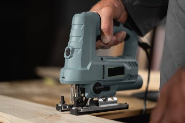 Tahta kesilirken elektrikli testere işçinin elinde, yakın plan.