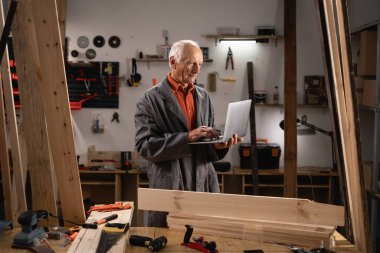 Üst düzey Carpenter, Bilgisayar kullanarak Ahşap Atölyesinde çalışıyor. Boşluğu kopyala