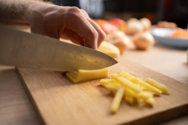 Yakından bakınca, tahta tahtada patatesler kesiliyor.