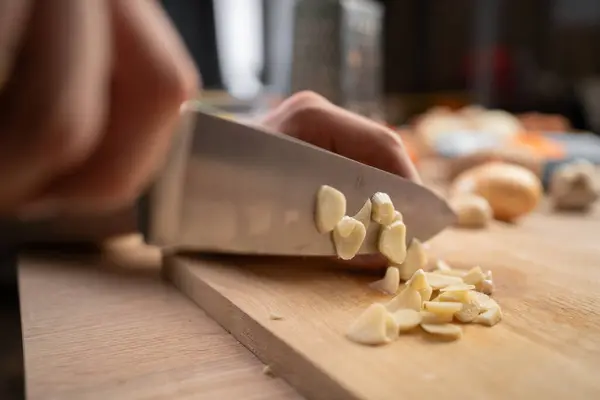 Stock image Male hand chopping garlic with kitchen knife on wooden board for cooking. Close-up