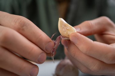 Adam ev mutfağında yemek pişirdiği için elle sarımsak soyuyor. Yakın plan.