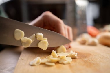 Tahta bir masada sarımsak. Şefin elleri tahta tahtada sarımsak doğruyor. Yemek sosu, yakın plan.