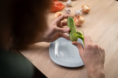 Mutfağındaki ahşap masada salatalık soyan adamın en iyi görüntüsü.