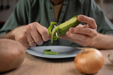 Salata için salatalık soyan adam ev mutfağındaki ahşap masada, yakın plan.