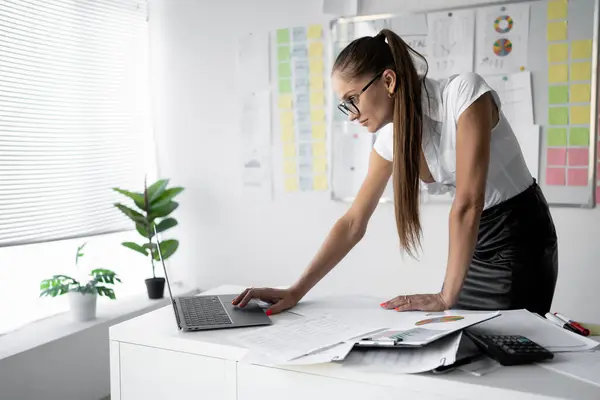 stock image Businesswoman working with laptop in office on financial result, prepares report, accountant typing on computer keyboard. Copy space