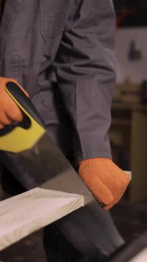 Yaşlı marangoz, atölyesinde ahşap testereyle odun kesiyor, kapatıyor.