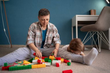 Milenyum kadını ve küçük oğlu birlikte eğitim oyunları oynuyorlar, evde oturuyorlar. Çocukların gelişim aktiviteleri. Boşluğu kopyala