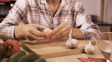 Mutfaktaki ahşap masada sebze salatası için haşlanmış yumurta soyan kadın. Yakın plan.