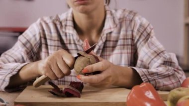 Kadın şef pancar soymak ve diyet sebze salatası hazırlamak için bir sebze bıçağı kullanır.