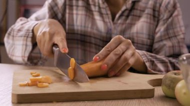 Ev mutfağında havuç kesen, yemek hazırlayan bir kadın. Kapatın.