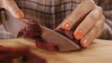 Kadın aşçı pancar kökünü bıçakla keser ve pancar çorbasını ev mutfağında hazırlar. Sebze. Yakın plan.