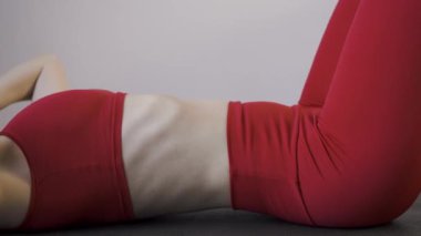 Eğitim, egzersiz ve sağlık konsepti. Kırmızı spor giysili atletik kadın abdominalleri pompalıyor. Fit kadın evde yerde karın kası egzersizi yapıyor. Yakın plan. spor, fitness ve sağlıklı yaşam tarzı