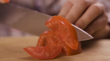 Kadın eli kesme tahtasında domates keserken yakın plan. Evde yemek pişirme kavramı. Yakın plan.