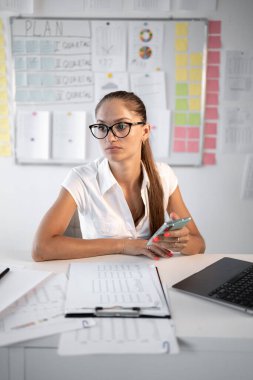 Ofisteki depresyondaki üzgün ve hayal kırıklığına uğramış kadın ellerinde akıllı telefon kullanarak kötü haberler okuyor, düşünceli iş kadını. Dikey görünüm