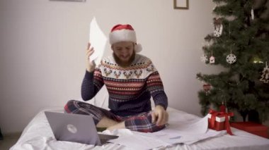 Noel Baba şapkalı sakallı adam, kızgın işadamı evrak işlerinde sorun yaşıyor, stresli görev sorunları, Noel sabahı evde evrak işleriyle uğraşıyor. Boşluğu kopyala