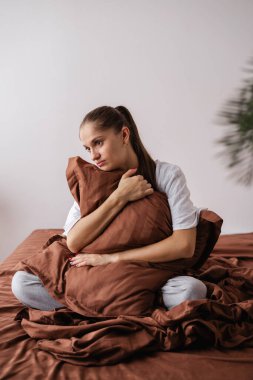 Yalnız esmer, uzun saçlı kadın yatak odasındaki yatakta oturup yastığa sarılıyor. Evde depresyonda bir kadın var. Boşluğu kopyala