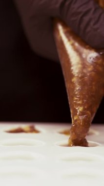 Şekerleme kalıbı şeker karamelli şekerlemeyle dolu. El yapımı çikolatalı şekerlemeler yapma süreci. Yakın plan. Dikey video