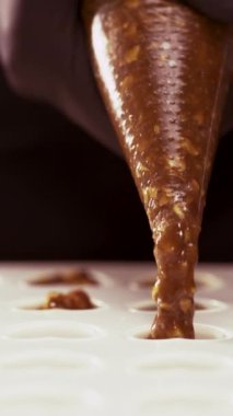 Şekerleme kalıbı şeker karamelli şekerlemeyle dolu. El yapımı çikolatalı şekerlemeler yapma süreci. Yakın plan. Dikey video