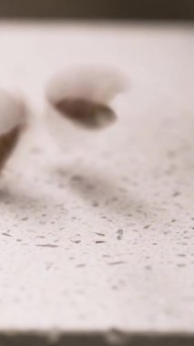 Beyaz kesme tahtasına düşen fındıklı cevizlere yakın çekim. Dikey video