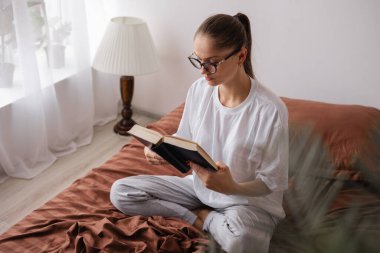 Gözlüklü İspanyol kadın evde kitap okuyor. İnsanlar ve dinlenme kavramı