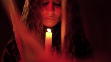 Sanat videosu fantazisi gotik kadın elinde tutuyor ve üfleme mumu söndürüyor. Şeytani tehlike. Karanlık odada siyah elbiseli bir kız. Boşluğu kopyala