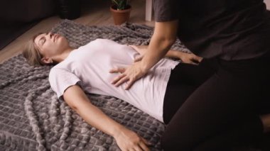 Masör, kadın Japon karın masajı egzersizlerini evde bir ekoseyle yapıyor. Shiatsu masajı
