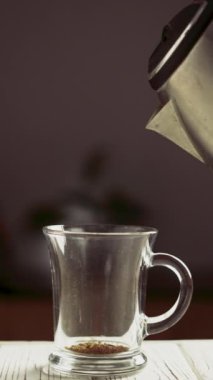 Siyah arka planda cam bardakta hazır kahveye sıcak su dökmek. Çözünmüş kahve hazırlanıyor. Dikey video