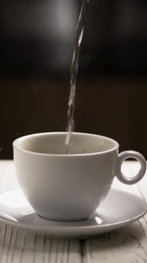 Sabahları kahve fincanına sıcak su dökmek. İnsanlar sıcak espresso kahvesi yapar. Dikey görünüm