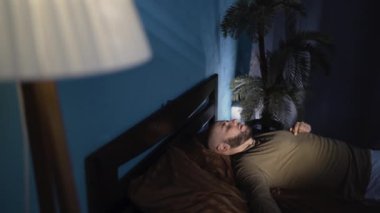 Uykusuzluk ve uyku kavramı. Geceleri yataktaki uykusuz adam. Sorun ve uyku bozukluğu. Çalar saat. Kabus, acı ve stres içinde üzgün bir adam. Boşluğu kopyala