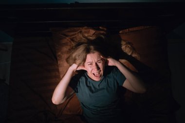 Dissatisfied irritated frustrated woman lying in bed scream hold head spend time in bedroom, suffering insomnia and anxiety. Bad mood concept clipart