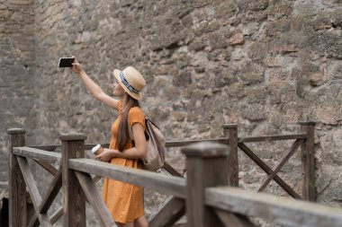 Elinde tarihi kaleyi gezen bir kadının fotoğrafını tutuyor. Sosyal medya kavramında mobil fotoğrafçılık ve tatil fotoğrafı.