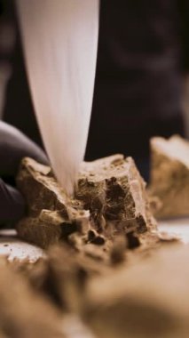 Şekerci ya da çikolatacı, şeker ve çikolata tatlısı yapmak için bir parça çikolatayı bıçakla doğruyor. Boşluğu kopyala