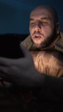 Adam gece yatakta metresiyle konuşuyor. Akıllı telefon kullanıyor, video görüşmeleri yapıyor. Boşluğu kopyala