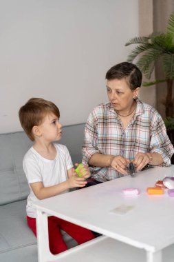 Orta yaşlı anne ve küçük oğlu evdeki oturma odasındaki masada hamur ya da plastikle heykel yapıyorlar. aile, yaratıcılık ve zanaat kavramı