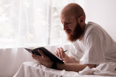 Beyaz sakallı bir adam pijama giyer ve iç mekandaki günlüklerine not alır. Blogcu dizüstü bilgisayarda yayınlama oluşturur. Boşluğu kopyala
