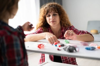 Mother and son creating toy figures out of clay during a peaceful afternoon at home, crafting handmade shapes while spending quality time together and strengthening their family connection