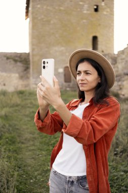 Yaşam tarzı konsepti olarak seyahat etmek. Genç bir kadın eski şatoda yürüyüş yapmaktan hoşlanıyor. İspanyol kadın akıllı telefondan selfie çekiyor. Boşluğu kopyala