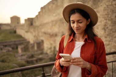 Eski kale ya da kalede telefon kullanan mutlu İspanyol kadın. Yaşam tarzı, seyahat, turizm ve blog konsepti.