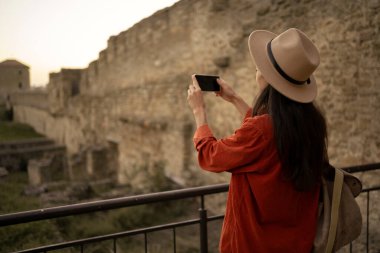 Turizm blogunda yayınlanmak üzere boş zamanlarında eski kalenin resimlerini çeken kadın turist. Yaşam tarzı, seyahat ve teknoloji konsepti