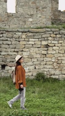 Turne boyunca şık bir bayan turist, eski ortaçağ Avrupa kalesinde yürüyor taş duvar boyunca el kamerasıyla yürüyor. Boşluğu kopyala.