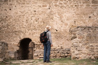 Turist, antik şatonun taş duvarının yanında duran antik kaleyi geziyor. Boşluğu kopyala